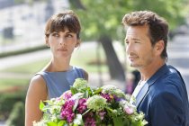 Couple élégant avec bouquet de fleurs debout à l'extérieur — Photo de stock