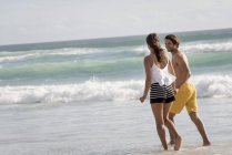 Jovem casal andando na praia de mãos dadas — Fotografia de Stock