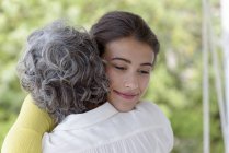 Nahaufnahme einer Mutter, die ihre erwachsene Tochter im Freien umarmt — Stockfoto