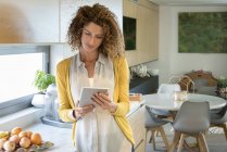 Frau nutzt digitalen Tisch in moderner Küche — Stockfoto