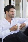 Счастливый человек за чашкой кофе на террасе — стоковое фото