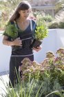 Jovem mulher no avental jardinagem ao ar livre — Fotografia de Stock