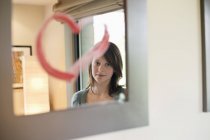 Teenage girl looking at reflection in mirror decorated with heart shape — Stock Photo