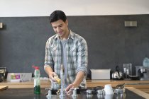 Hombre sonriente lavando platos en la cocina moderna - foto de stock