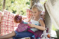 Маленькая девочка держит игрушки в домике на дереве — стоковое фото