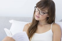Крупный план молодой женщины, читающей книгу в постели — стоковое фото