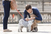 Homem anexando trela no cachorro na rua na cidade — Fotografia de Stock
