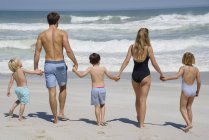 Vue arrière de la famille marchant sur la plage tenant la main — Photo de stock