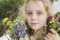 Retrato de niña rubia sosteniendo flores - foto de stock