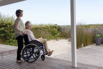 Hombre mayor en silla de ruedas con su esposa en el porche - foto de stock