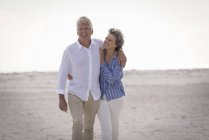Feliz casal sênior romântico andando na praia — Fotografia de Stock