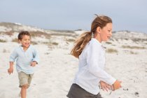 Junge spielend mit seine sister auf die strand — Stockfoto