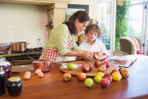 Grandmother and little boy peeling fruit at home — Stock Photo