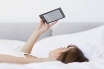Frau liegt mit digitalem Tablet im Bett — Stockfoto