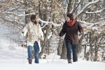 Молода пара катається на снігоступах в зимовому лісі — стокове фото