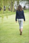 Vista posteriore della ragazza che cammina in campo verde — Foto stock