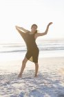 Elegant young woman in black dress posing on beach — Stock Photo