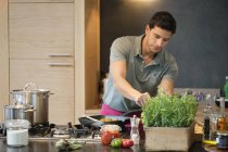 Mann bereitet Essen in moderner Küche zu — Stockfoto