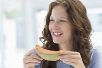 Nahaufnahme einer lächelnden sommersprossigen jungen Frau, die Melone isst — Stockfoto