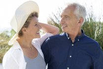 Glückliches Seniorenpaar lächelt, während es im Garten steht und einander ansieht — Stockfoto