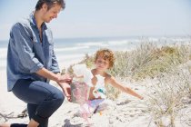 Hombre adulto y su hijo limpiando la playa - foto de stock