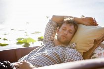 Relaxado jovem dormindo em barco no lago no campo — Fotografia de Stock