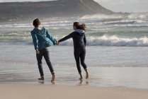 Glückliches junges Paar läuft Händchen haltend am Strand — Stockfoto