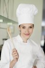 Retrato de una cocinera feliz sosteniendo una cuchara de madera - foto de stock