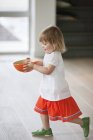 Little girl carrying a bowl of food at home — Stock Photo