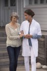 Женщина-медсестра помогает улыбающейся пожилой женщине в доме престарелых — стоковое фото