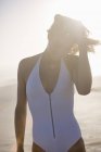 Улыбающаяся молодая женщина, стоящая на пляже и трогательные волосы — стоковое фото