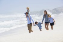 Famiglia felice con bambini che camminano sulla spiaggia — Foto stock