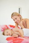 Женщина смотрит на своего ребенка спящего на кровати — стоковое фото