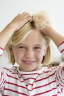 Портрет щасливої маленької дівчинки, що торкається світле волосся — стокове фото