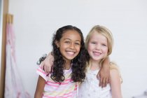 Портрет маленьких дівчат, які посміхаються і обіймаються на білому тлі — стокове фото