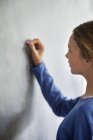 Крупный план девочки-подростка, пишущей на доске в классе — стоковое фото