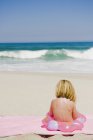 Little girl sitting with inflatable ring on sandy beach — Stock Photo