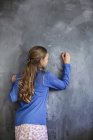 Gros plan de fille écrivant sur le tableau noir dans la salle de classe — Photo de stock