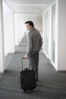 Uomo d'affari che trasporta bagagli in corridoio e si guarda alle spalle — Foto stock