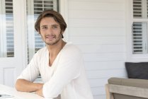 Happy young man sitting on terrace and looking away — Stock Photo