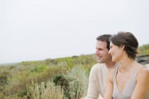 Happy couple sitting in nature together and looking at view — Stock Photo