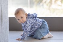 Baby girl crawling on floor at home — Stock Photo