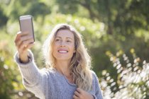 Sorridente donna matura prendendo selfie nel giardino estivo — Foto stock