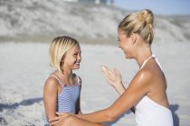 Усміхнена мати і дочка дивляться один на одного на пляжі — стокове фото