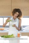 Mulher derramando suco de legumes em vidro na cozinha — Fotografia de Stock