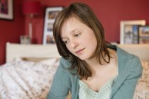 Teenage girl sitting on bed and thinking — Stock Photo