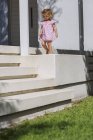 Cute baby girl walking on ledge in summer outdoors — Stock Photo