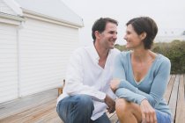 Couple smiling together in front of coastal house — Stock Photo