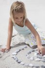 Blond girl playing with pebbles on beach — Stock Photo