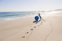 Хлопчик грає з пляжним м'ячем на піщаному узбережжі моря — стокове фото